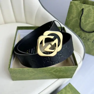 Black belt with a gold-coloured buckle coiled inside a green box