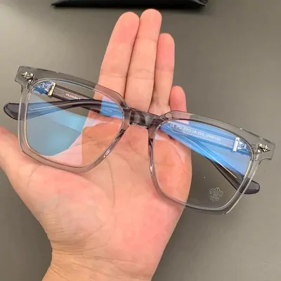 Clear square eyeglass frames with blue reflections held in a hand