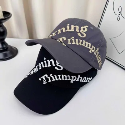 Two dark embroidered baseball caps with cream and white lettering