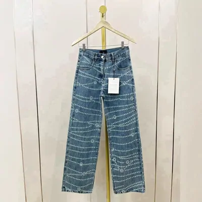 Wide leg patterned denim jeans on a wooden hanger against a white wall