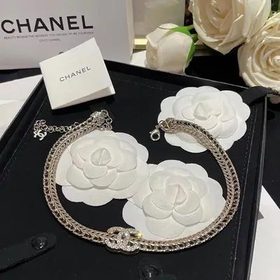 Silver-coloured chain on a black tray with white paper flower props